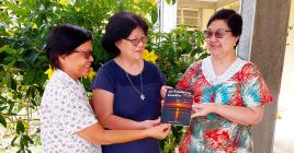 Françoise Mootoosamy, responsable du magazine Prions, remet une copie du livre La tradition Lorette aux co-leaders de Lorette, Sr Thérèse Yaw et Sr Marie Ange Lim. 